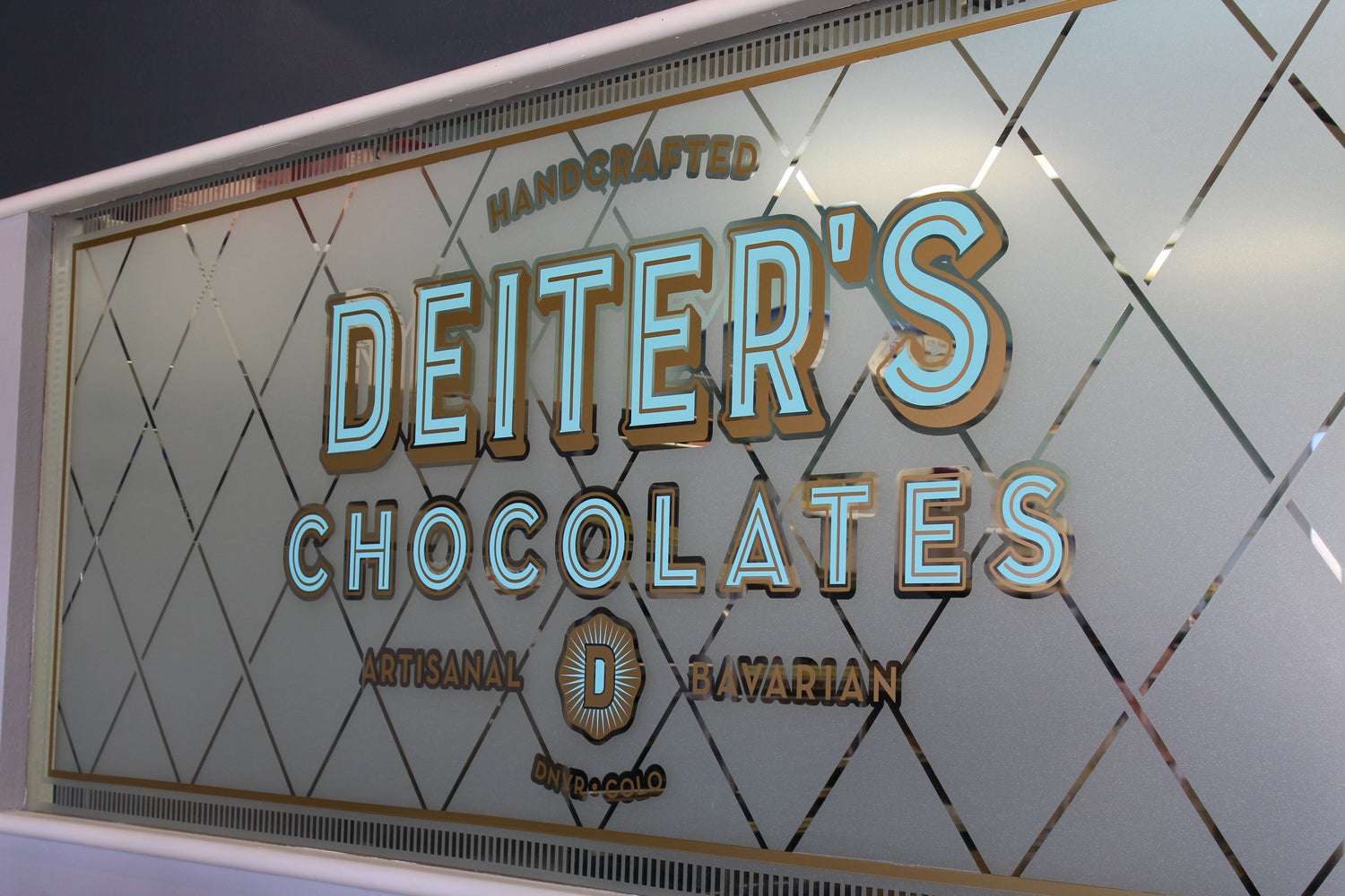 Our frosted glass window featuring our logo. Behind the window is our kitchen where the chocolatiers create our gourmet chocolate items.