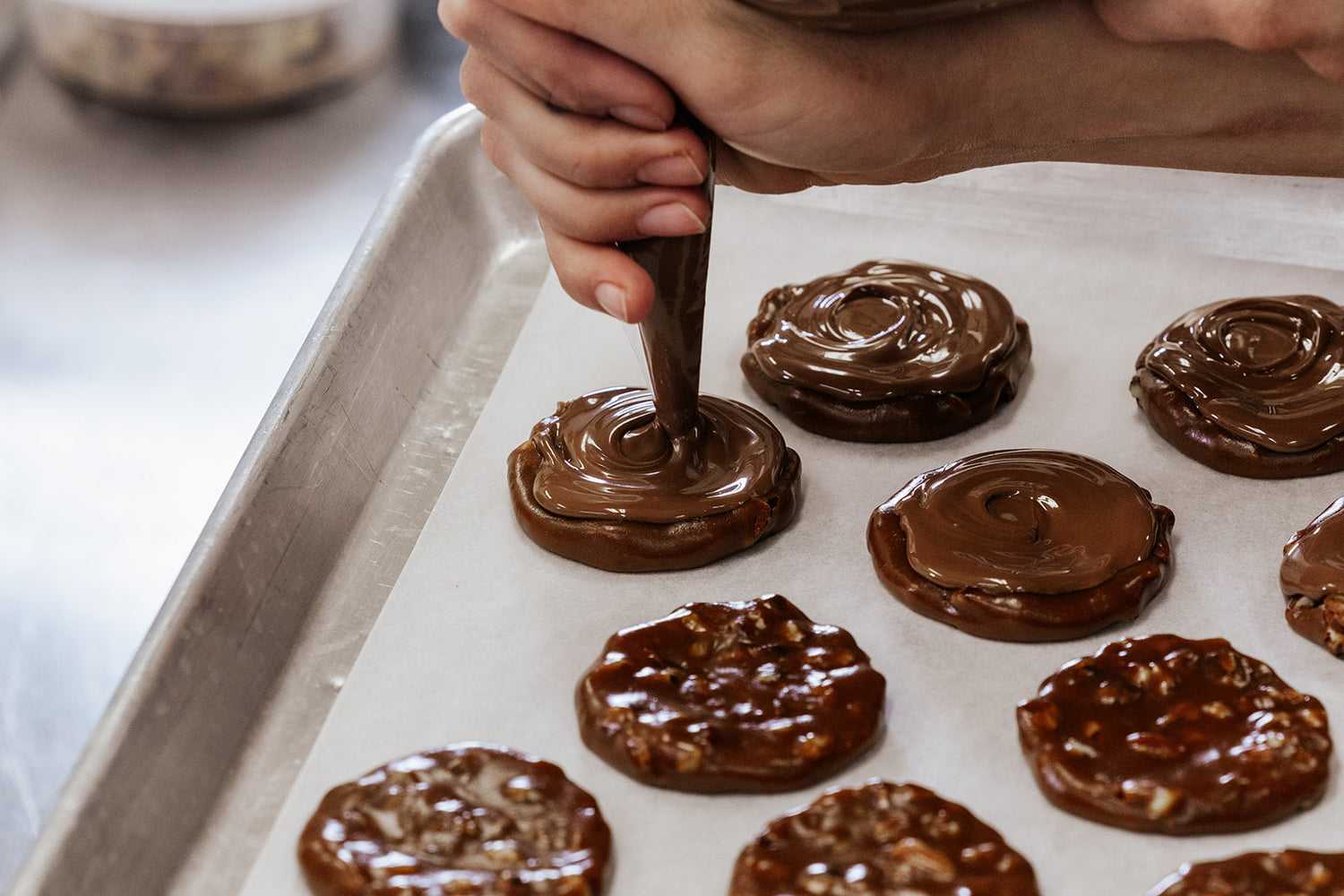 Piping chocolate onto caramel nut slider