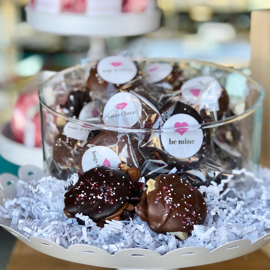 a glass bowl holding our caramel nut turtles with special valentine's stickers that say things like: Be Mine and Sweet Love