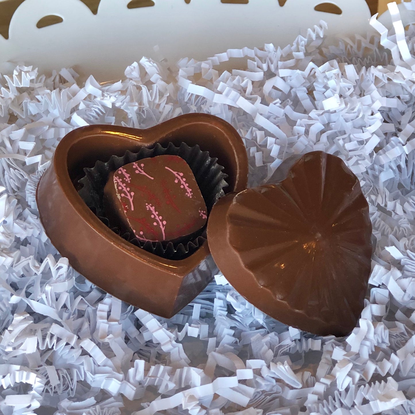 Milk chocolate heart box with lid, and one truffle inside